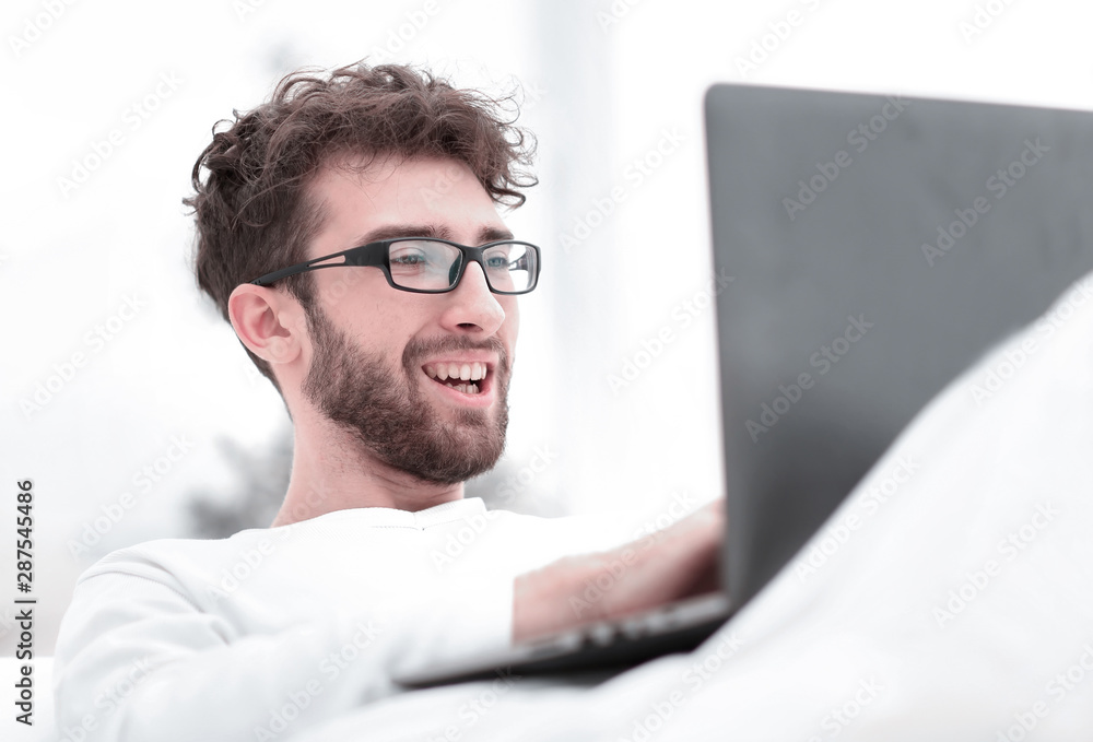handsome man working on laptop lying on bed handsome man working on laptop lying on bed