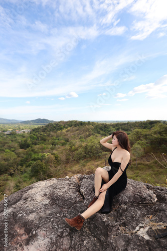 full length young beautiful asian woman  long hair in black dress sitting in nature outdoors with peaceful and happy face on mountain during holiday vacation