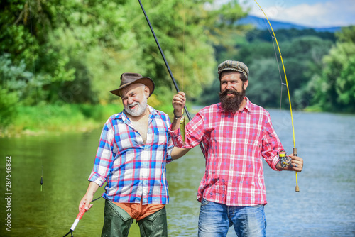 Bearded men catching fish. Mature man with friend fishing. Summer vacation. Happy cheerful people. Family time. Fisherman with fishing rod. Activity and hobby. Fishing freshwater lake pond river