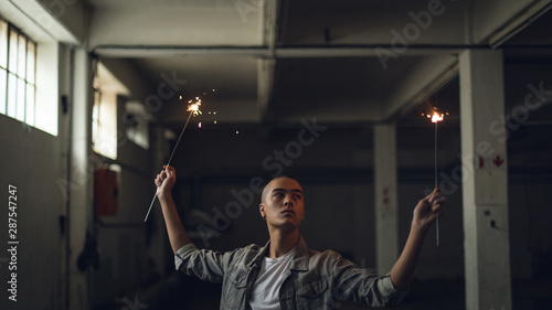 Young man holding spakles inside an empty warehouse photo