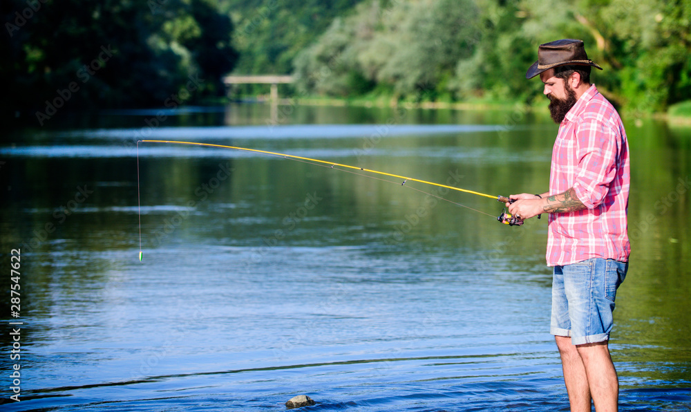 Man at riverside enjoy idyllic landscape while fishing. Fishing cause negative physiological effects for fish populations. Environmental impact of fishing includes issues such as availability of fish Man at riverside enjoy idyllic landscape while fishing. Fishing cause negative physiological effects for fish populations. Environmental impact of fishing includes issues such as availability of fish