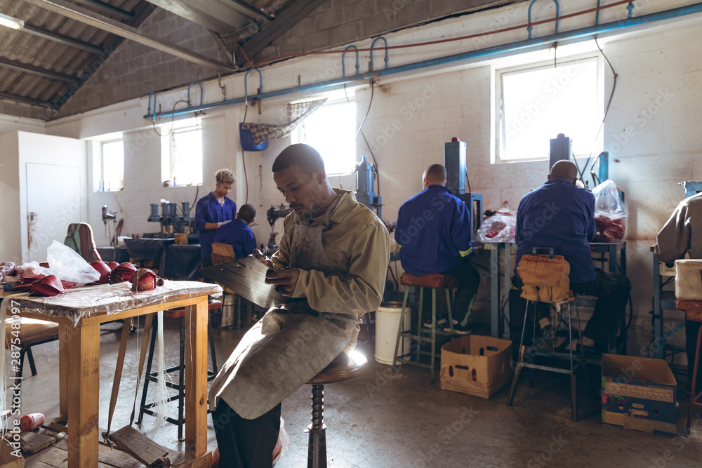 Young man holding a clipboard and writing in a cricket ball factory Young man holding a clipboard and writing in a cricket ball factory