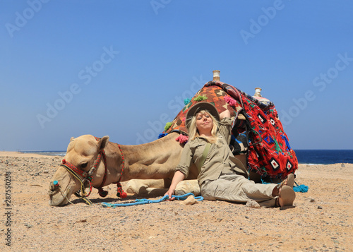 eine blonde Frau im Urlaub in Ägypten ruht sich neben einem Kamel aus