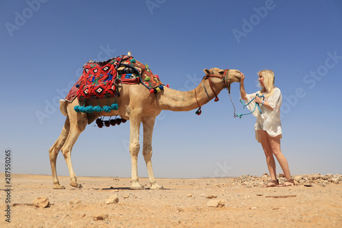 eine blonde Frau streichelt ihr Kamel in der Wüste