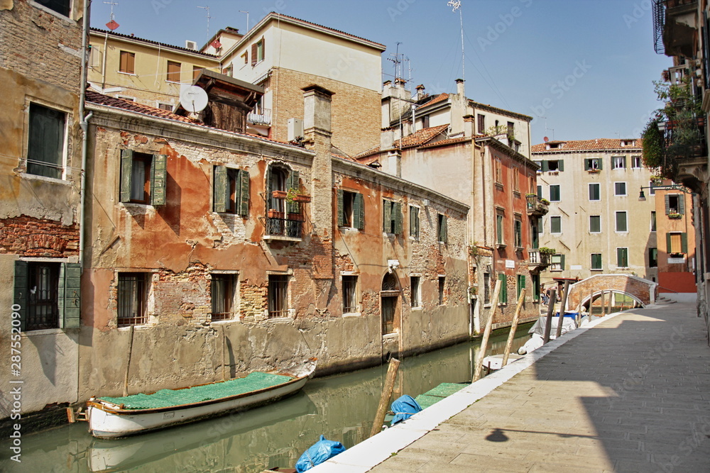 Very old buildings in Venice. Canal with boats. Empty street
