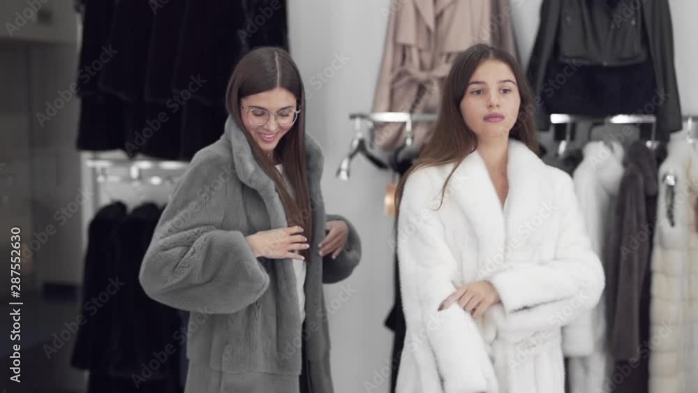 Handheld shot of two female models, doing a catwalk while wearing fur coats in a shopping store Handheld shot of two female models, doing a catwalk while wearing fur coats in a shopping store
