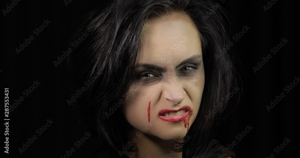Fototapeta premium Vampire Halloween makeup. Woman portrait with blood on her face.