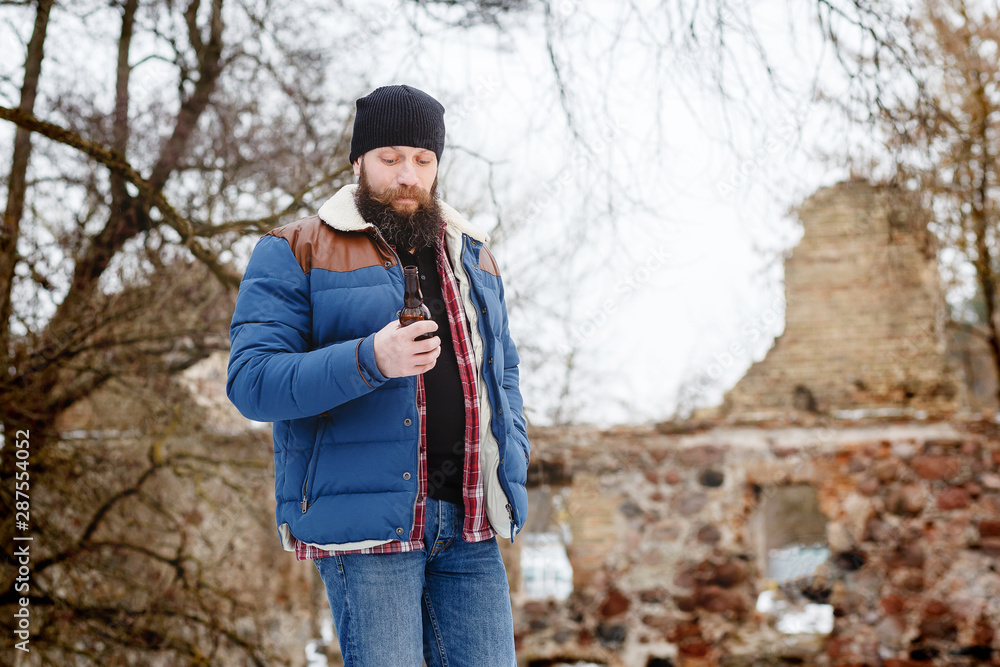bearded man drinking beer in winter in the forest bearded man drinking beer in winter in the forest