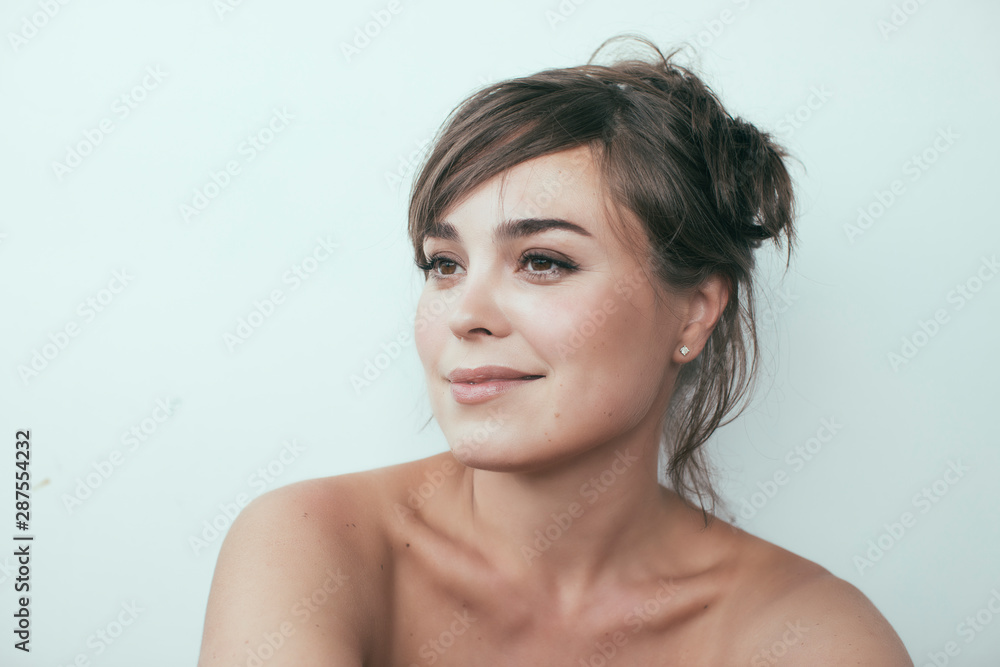 Close up of young attractive confident white woman with beautiful skin and gentle smile. Brunette, hair up. White background. Close up of young attractive confident white woman with beautiful skin and gentle smile. Brunette, hair up. White background.