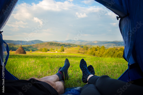 Two people lying in tent, view from inside. Couple camping with beautiful view of mountains photo