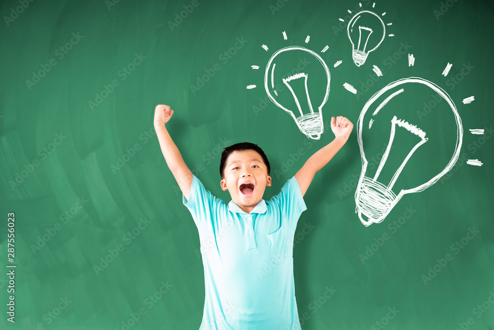 happy asian boy standing against chalkboard with idea bulb concepts