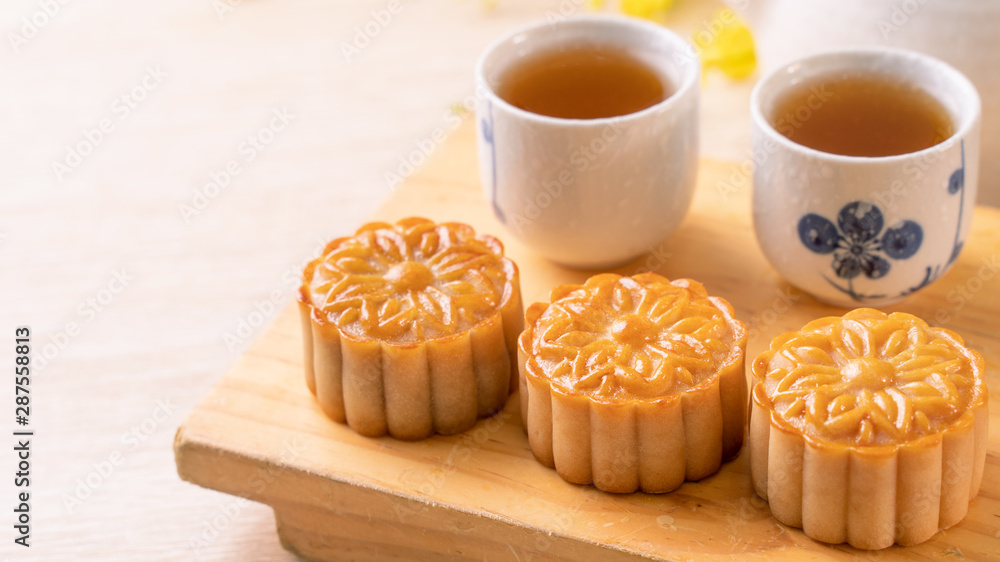 Moon cakes with tea on bright wooden table and serving try, holiday concept of Mid-Autumn festival traditional food layout design, close up, copy space. Moon cakes with tea on bright wooden table and serving try, holiday concept of Mid-Autumn festival traditional food layout design, close up, copy space.