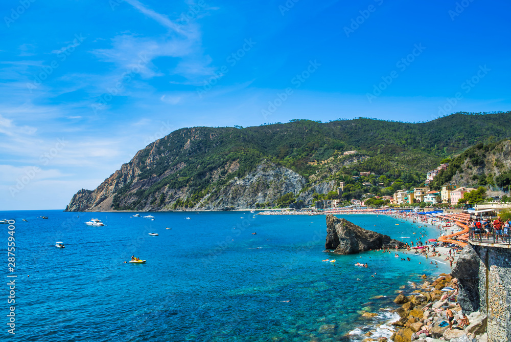 Monterosso al Mare, La Spezia province, Italy - August 17, 2019: city beach in the summer season / big beach in Liguria / vacation in Italy / protruding cliffs in the sea, boats and yachts