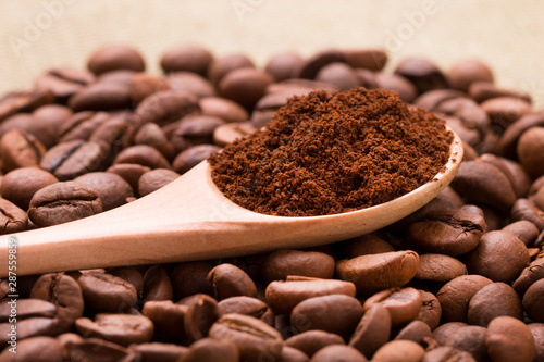Ground coffee in a wooden spoon. Ground coffee in a spoon on a background of whole beans closeup. Sprinkled coffee beans.