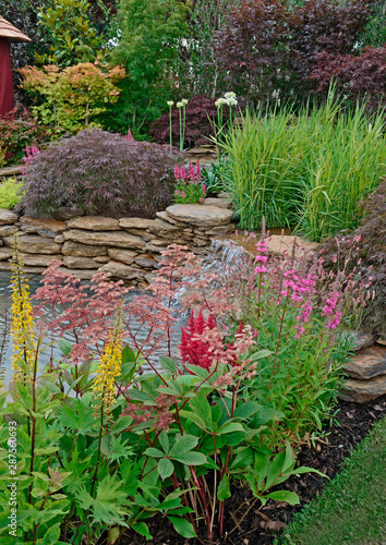 The pond area of an aquatic garden with planted rockery flowers and waterfalls