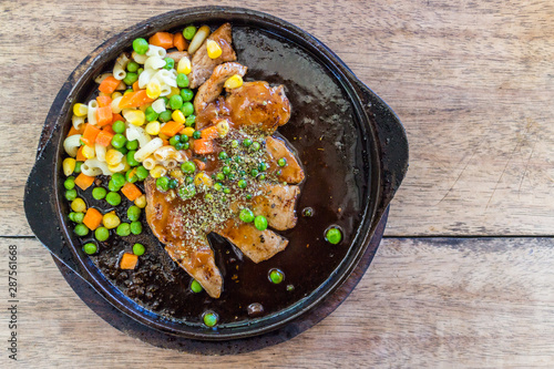 pork chops Steak corn, peas and carrots served in a hot pan.