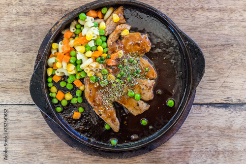 pork chops Steak corn, peas and carrots served in a hot pan.