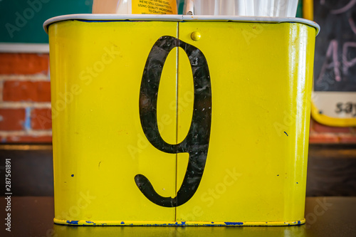 A Black Number Nine on a Yellow Tin Container