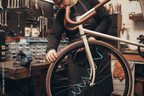 Mechanic repairing a mountain bike in a workshop.