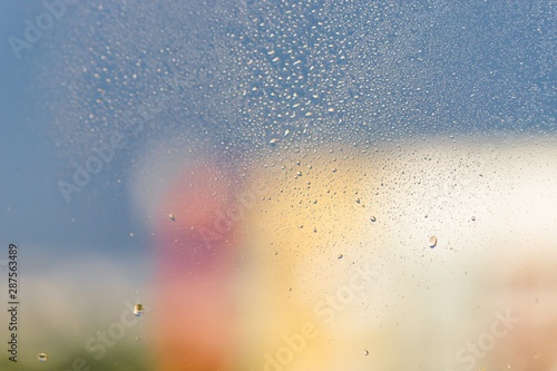 Raindrops on window glass. Gray, pink, yellow background, copy space