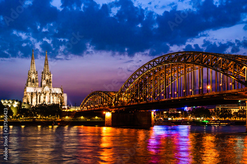 Beautiful night landscape of the Cologne, Germany with gothic cathedral, railway and pedestrian Hohenzollern Bridge and reflections over the River Rhine