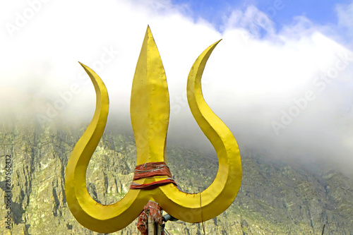 Trident weapon of lord shiva placed ahead of a cloudy mountain-image photo