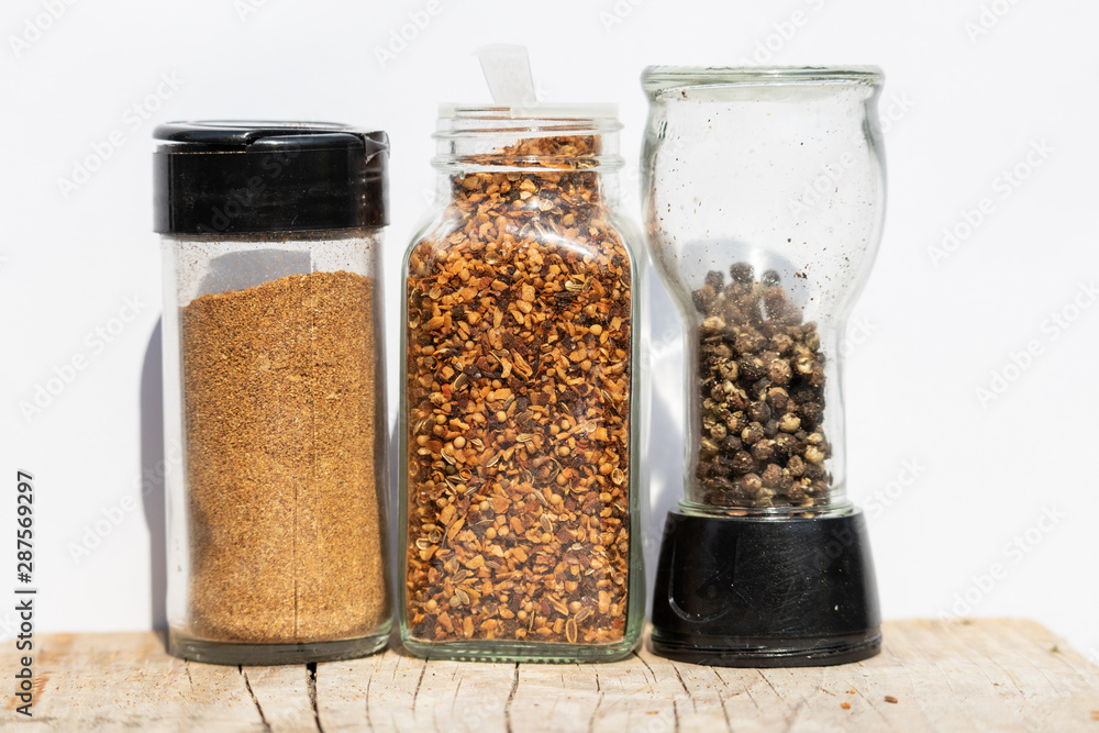 Three jars with spices of different grinding on a white backgrou Three jars with spices of different grinding on a white backgrou