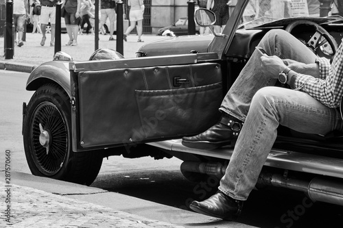 elegant man sitting in retro car on city street © Mykhailo