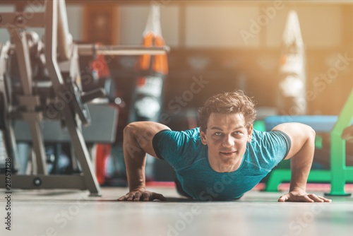 Portrait of adult athlete doing push-ups as part of bodybuilding training. Horizontal shot. Front view