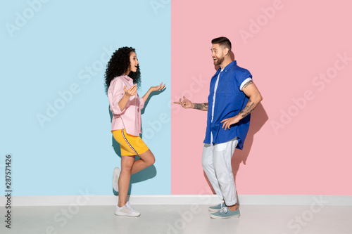 Young emotional caucasian couple in bright casual clothes posing on pink and blue background. Concept of human emotions, facial expession, relations, ad. Man and woman look astonished, happy.