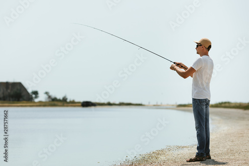 Young man fishing at sea from the shore. fisherman uses spinning