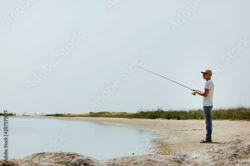 Young man fishing at sea from the shore. fisherman uses spinning