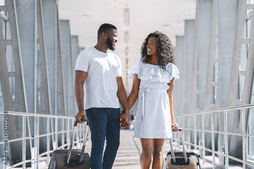 African american lovers going with luggage to vacation