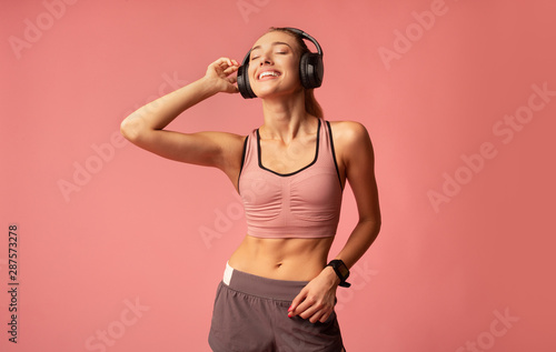Fitness Girl In Wireless Earphones Listening To Music, Pink Background © Prostock-studio