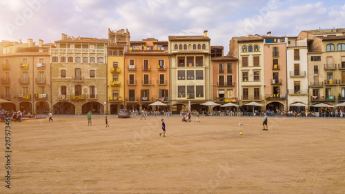 Vic Catalonia Spain Placa Major Main Square . Golden light. Summer time. People walking streets. Street life photo