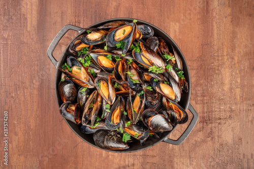 Marinara mussels, moules mariniere, cooked in a cooking pan, shot from above on a dark rustic background