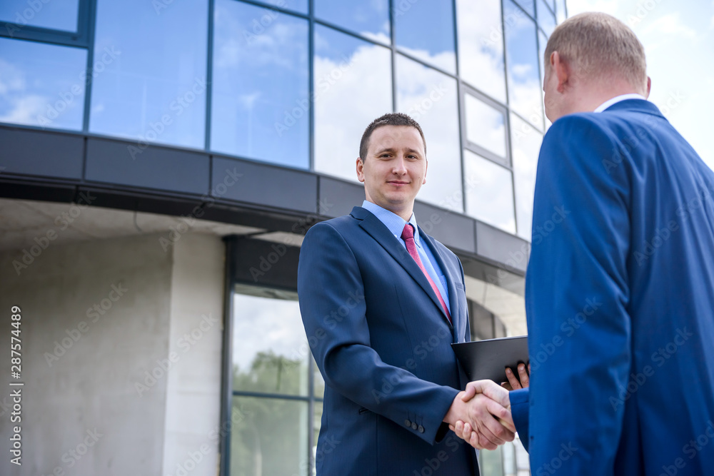 Businessmen making deal and handshaking outside building Businessmen making deal and handshaking outside building