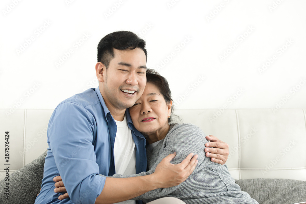 Asian mother hugging her son and sitting on sofa at home, lifestyle concept. Asian mother hugging her son and sitting on sofa at home, lifestyle concept.