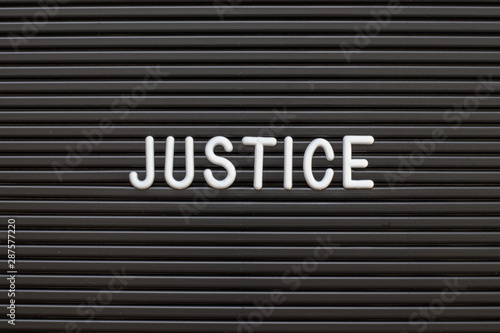 Black color felt letter board with white alphabet in word justice background