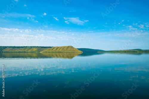 beautiful calm scenery landscape Ukrainian country side national reservation territory view with Dniester river smooth water surface and hill land horizon background in clear summer weather time 