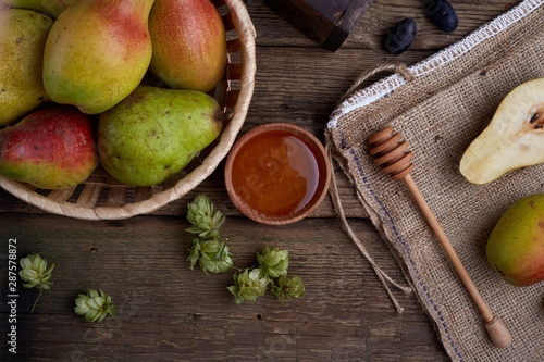 Flat lay with a pears with nuts on dark wooden background. With hops and honey.