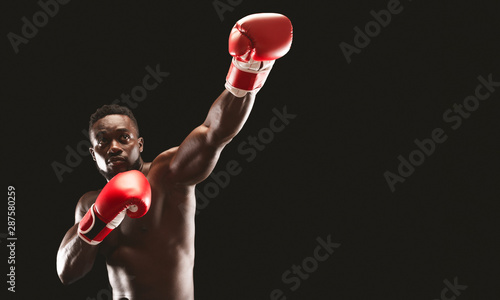 MMA african boxer showing big punch over black studio background
