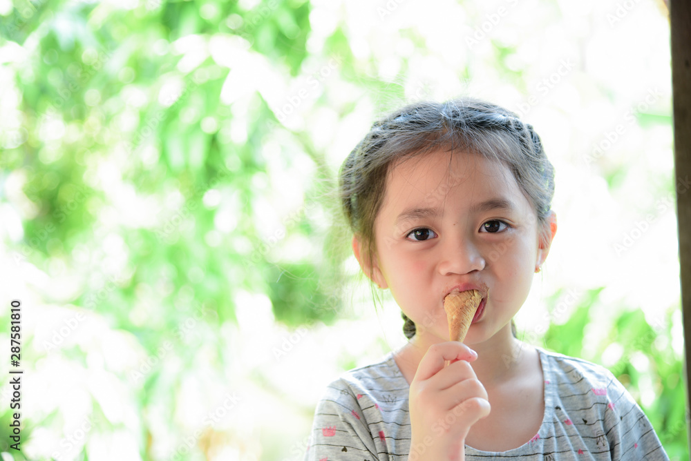 Happy child girl eating ice cream with blurred green background Happy child girl eating ice cream with blurred green background