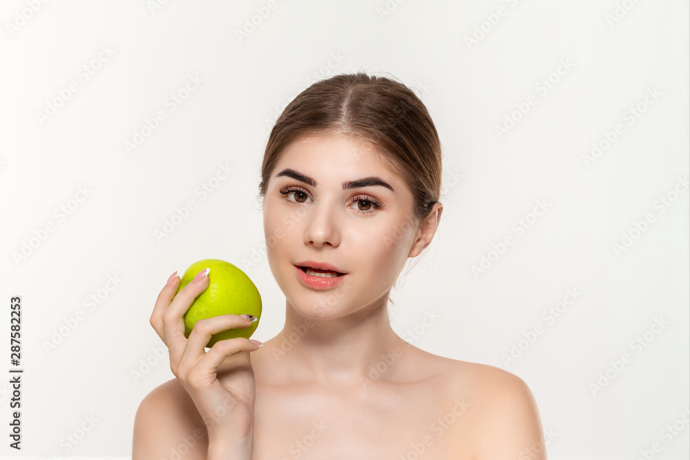 Close-up portrait of a happy beautiful young girl holding green apple isolated over white background. Concept of beauty and health care. Close-up portrait of a happy beautiful young girl holding green apple isolated over white background. Concept of beauty and health care.