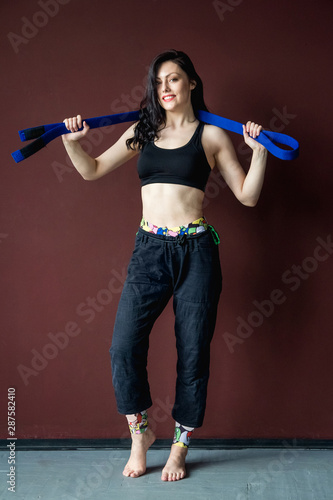 Beautiful athletic woman in black kimono with blue belt. Martial arts concept. Indoor, studio shot