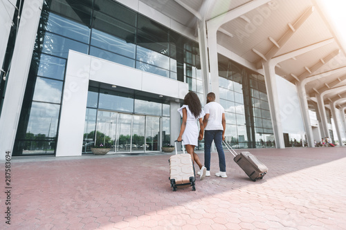 African millennial couple going to airport with suitcases