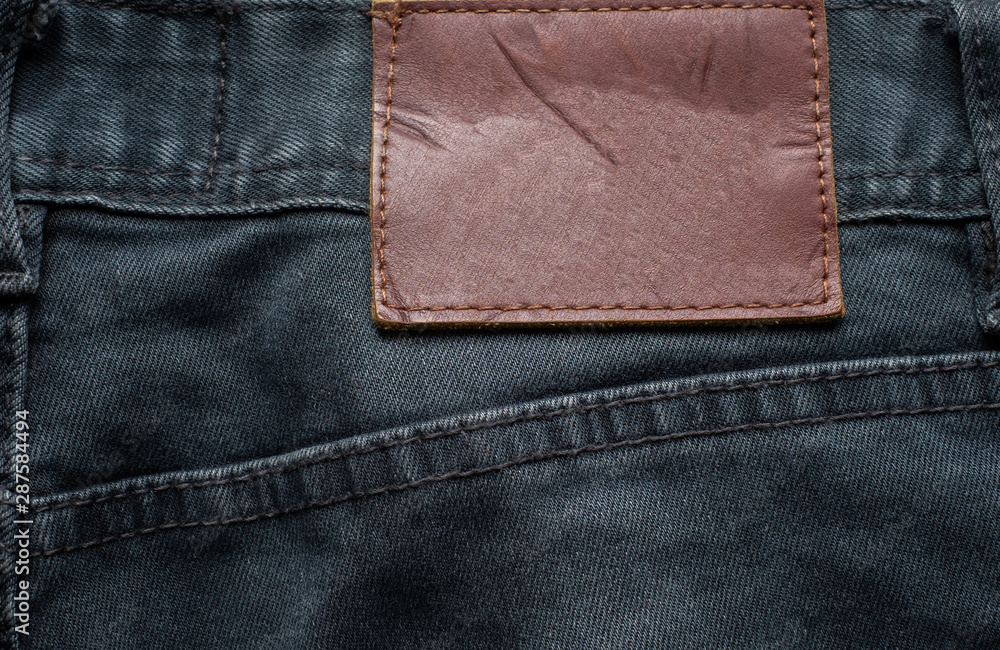 Macro, Close-up of blank leather label on new denim black jeans trousers. fashion and retro stlye on background.