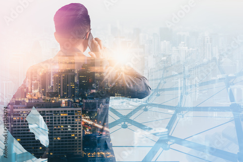 Photography The double exposure image of the business man using a smartphone during sunrise overlay with cityscape image
