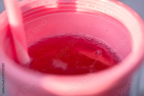 bubbles in a glass of soda, pink liquid pours from the bottle into the glass