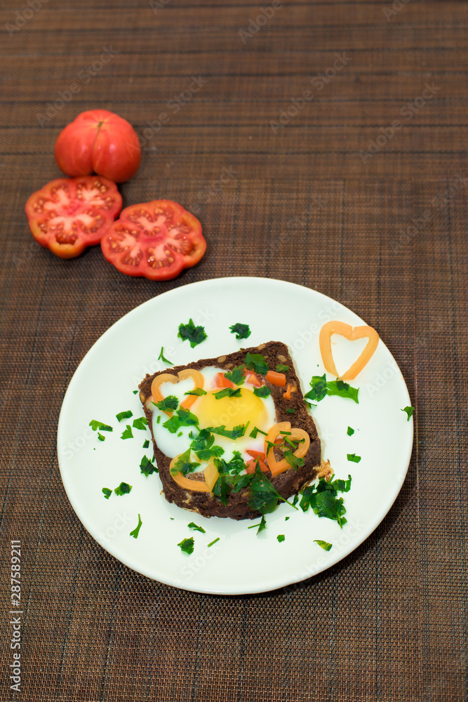 egg in bread with herbs and tomatoes on a Breakfast plate